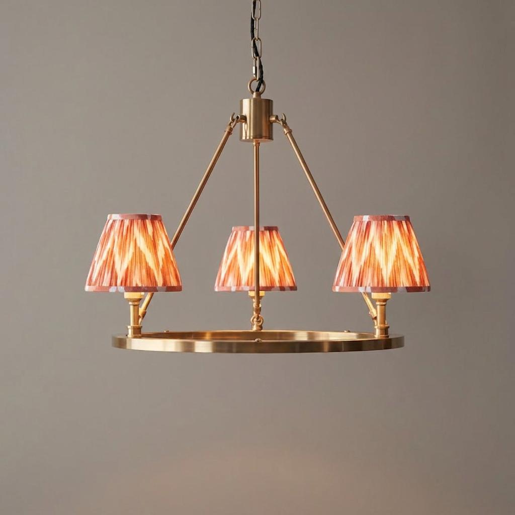 Brass circular ceiling pendant light with three orange zigzag patterned shades.