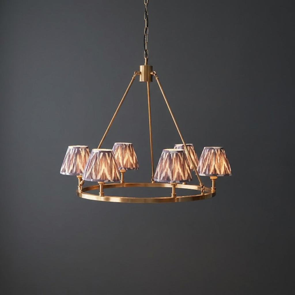 Large brass chandelier with a circular ring frame and six grey zigzag patterned shades against a dark background.