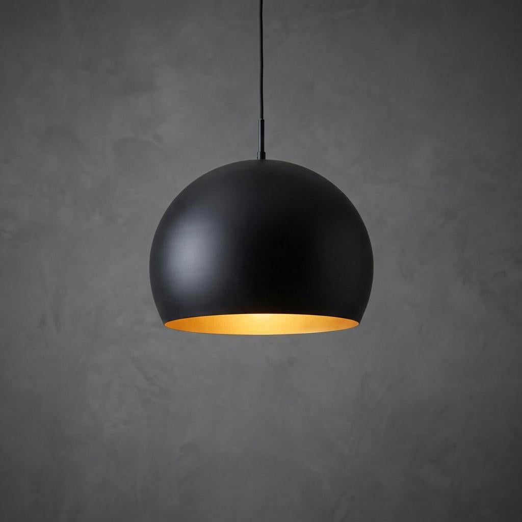 A matte black dome pendant light with a glowing gold interior against a textured grey wall.