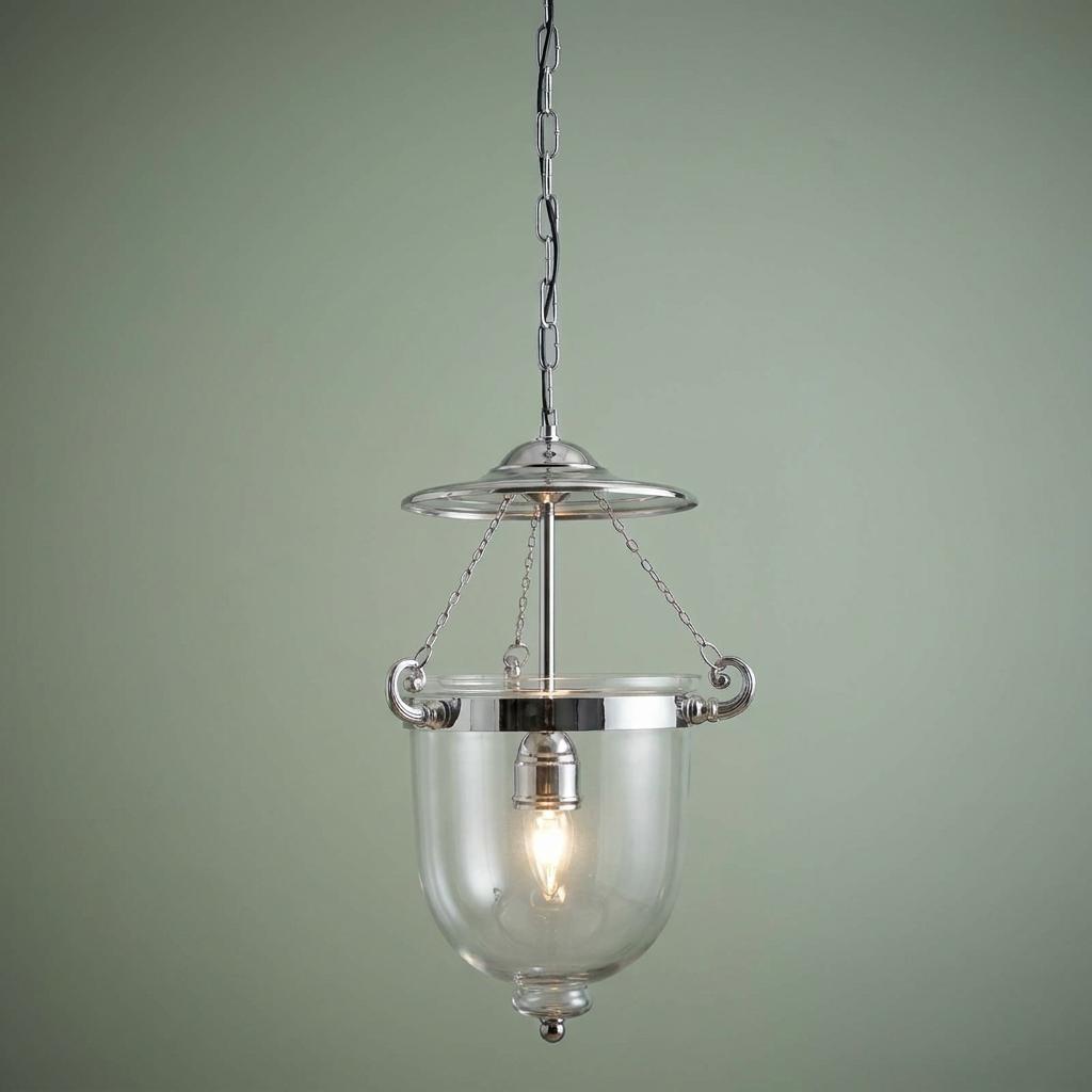 A chrome Georgian ceiling lantern with a clear glass bell jar and chain suspension against a green wall.
