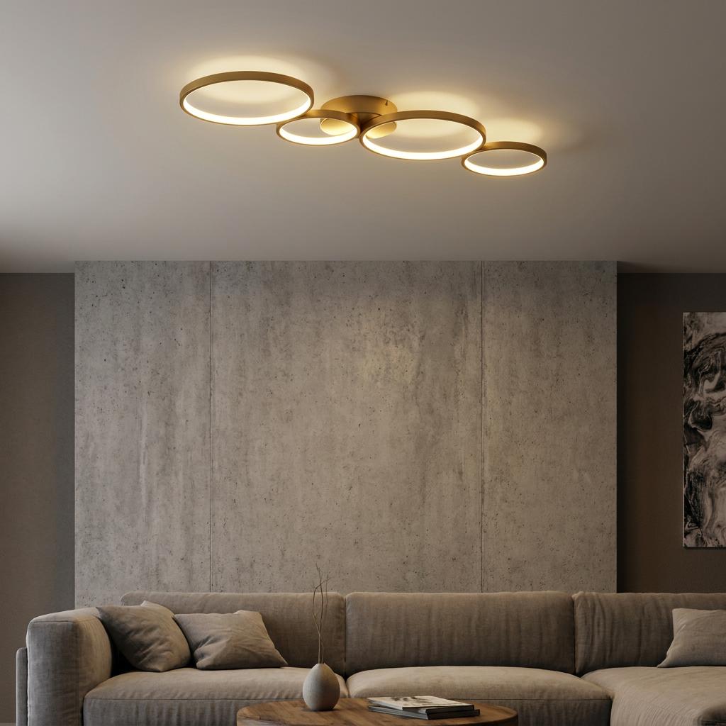 Four interlocking gold LED rings of a flush ceiling light illuminating a modern grey living room.