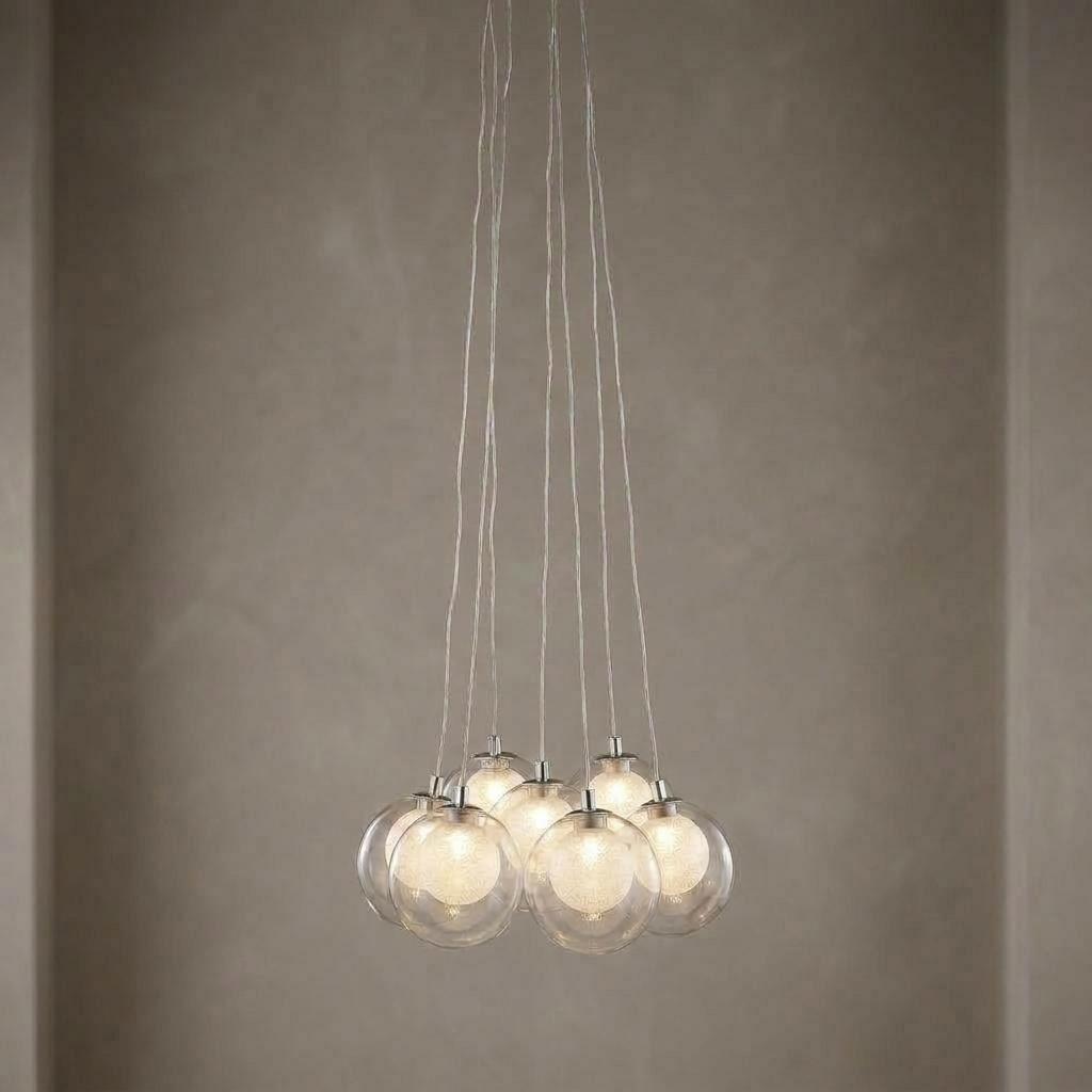 Cluster of seven glass globe pendants with glowing crystal LED centers suspended from thin cables.