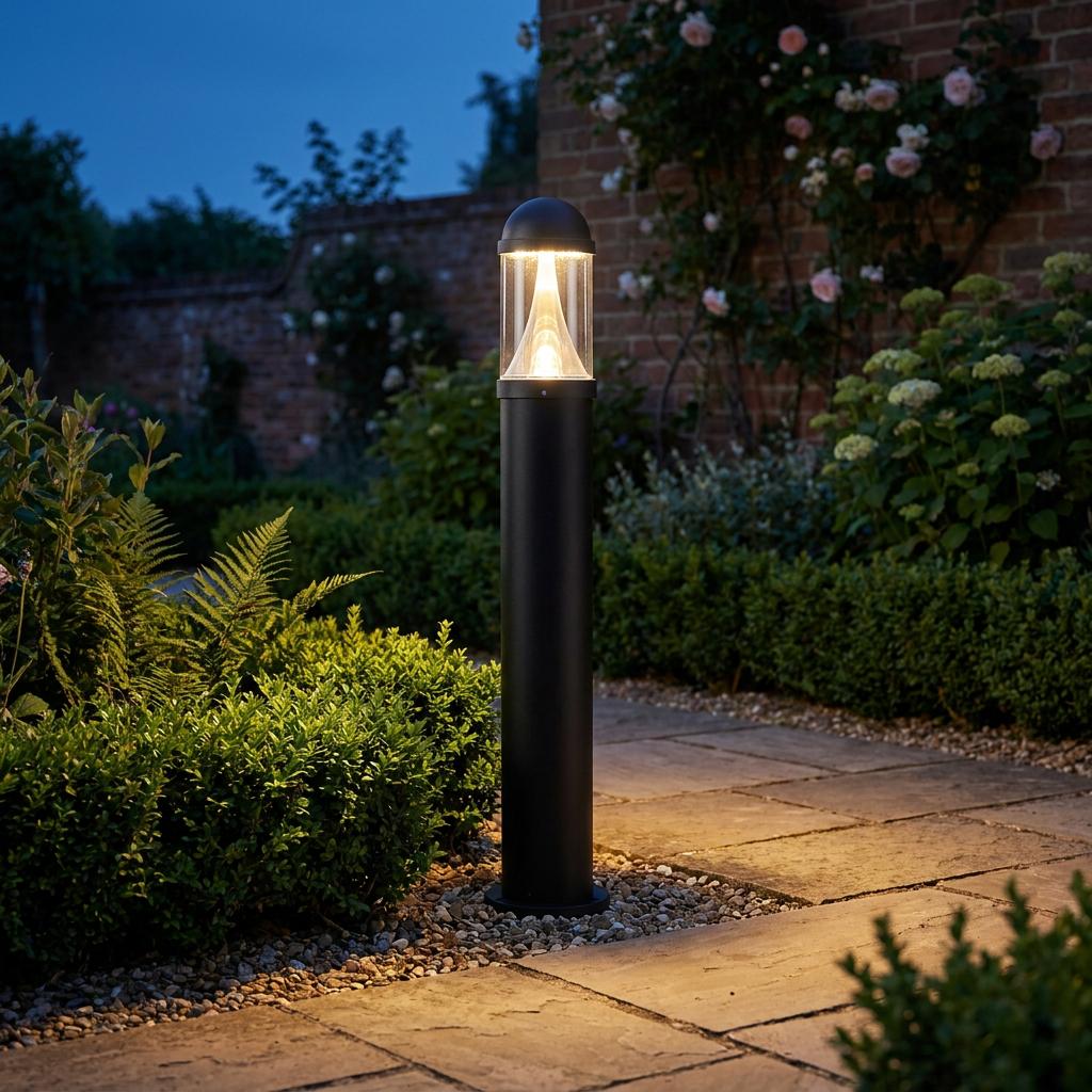 Black cylindrical bollard light illuminating a stone garden path at night with warm yellow light.