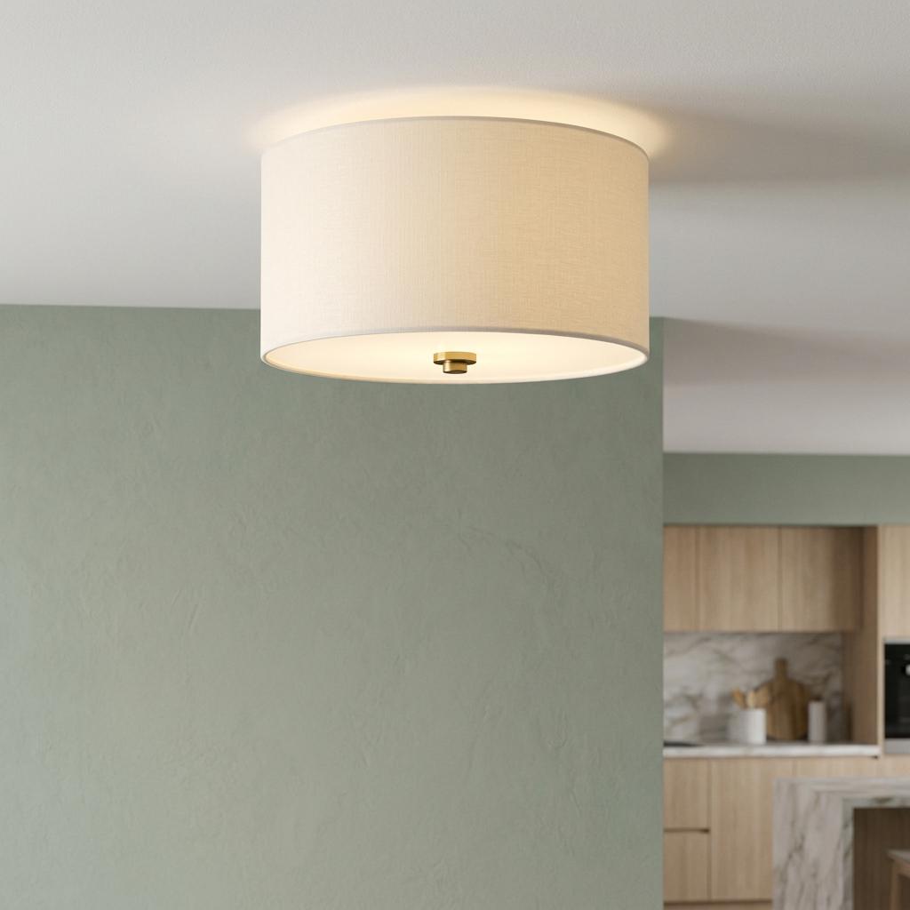 White drum shade flush mount ceiling light with a brass finial mounted on a ceiling near a sage green wall.