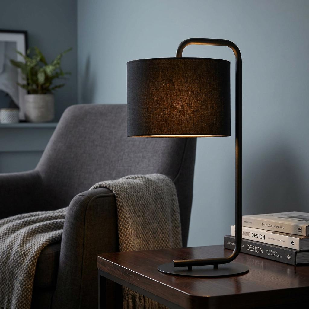 Black table lamp with a curved frame and fabric shade glows on a wooden table in a living room.