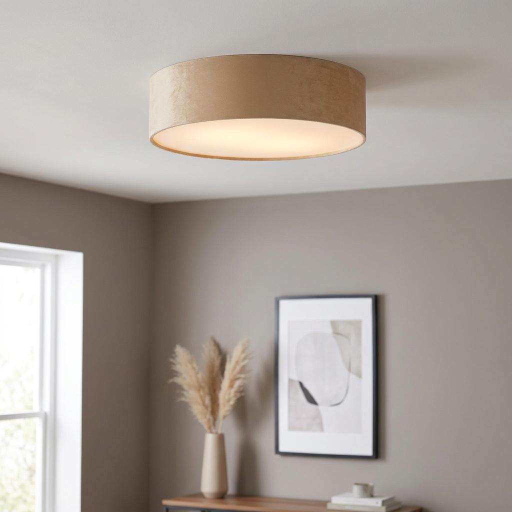 Champagne velvet drum flush ceiling light glowing in a modern living room with neutral walls.