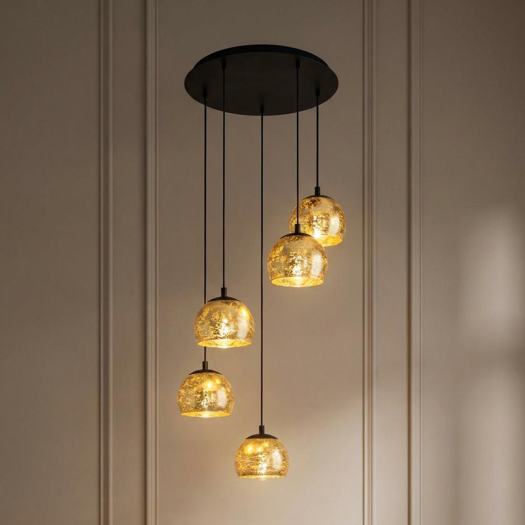 Staggered five-light pendant fixture with gold leaf spherical glass shades glowing against a paneled wall.