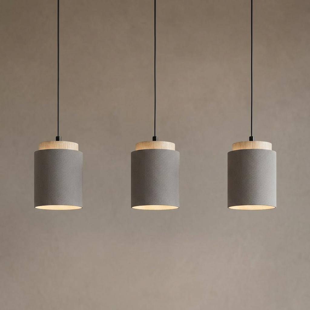 Three modern pendant lights with brown fabric shades and light wood accents hanging in a row against a neutral wall.