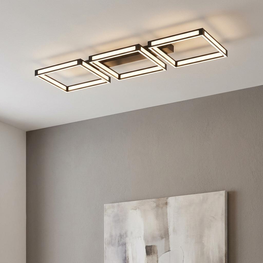 Three square-shaped black framed LED flush ceiling lights illuminating a modern interior.