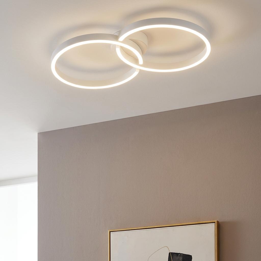 Interlocking white LED circular rings flush-mounted on a white ceiling above a neutral wall.