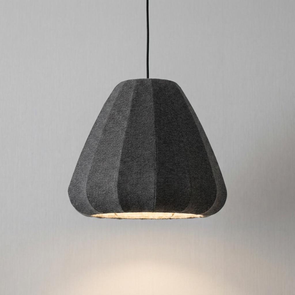 Modern dark grey fluted fabric pendant light illuminated against a light grey wall.