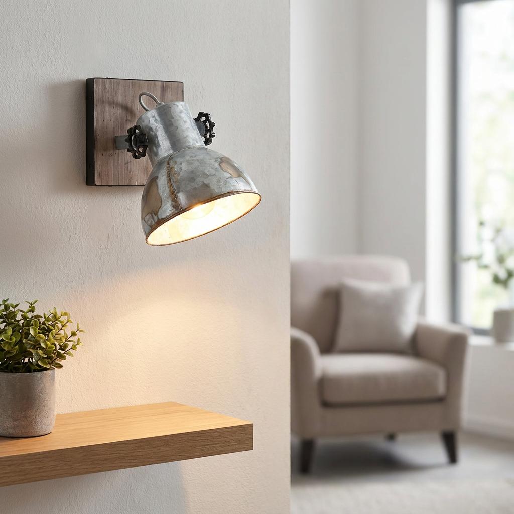 Industrial wall spotlight with a distressed steel shade and wood base, illuminating a shelf in a living room.