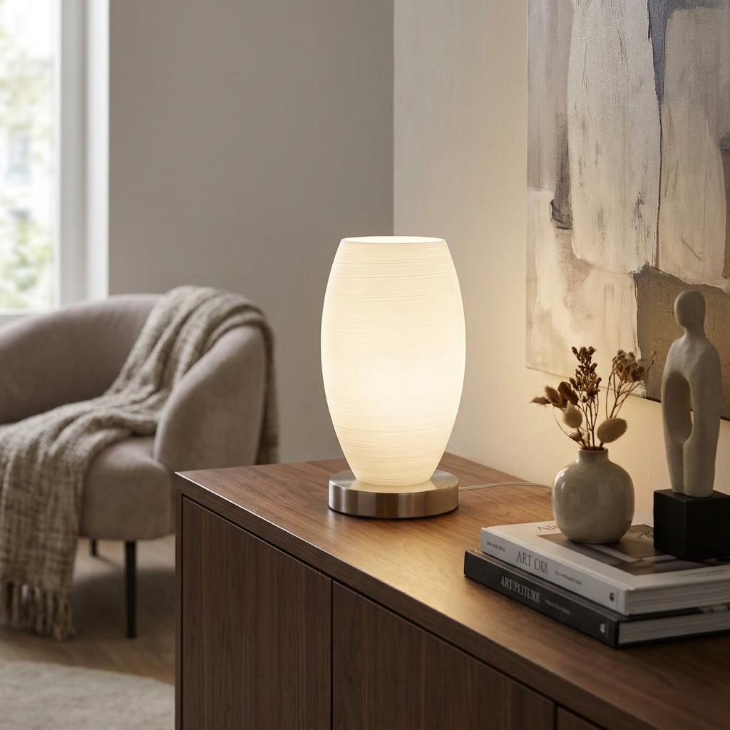 Eglo Batista 3 table lamp with a textured white glass shade glowing on a wooden sideboard in a living room.