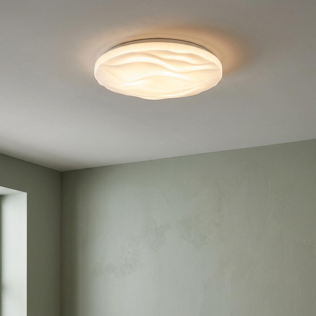 Round white LED flush ceiling light with a wavy textured diffuser illuminating a room with soft green walls.