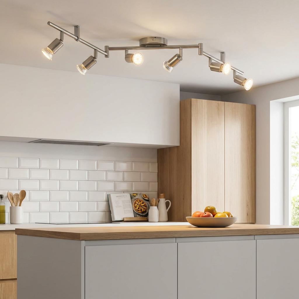 Six-light nickel bar spotlight mounted on a kitchen ceiling over a modern island with white subway tiles.