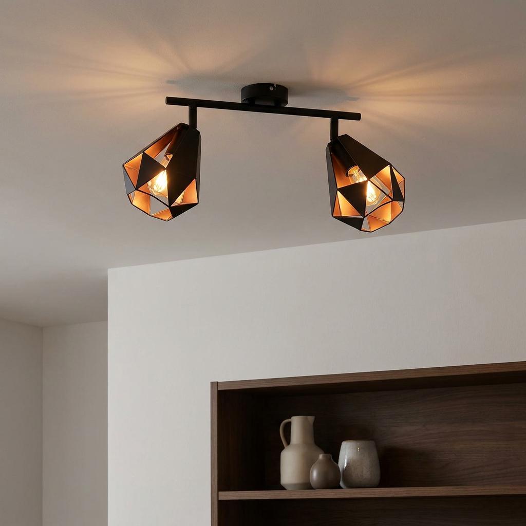 Black and copper geometric bar spotlight with two lights mounted on a white ceiling, casting warm light.