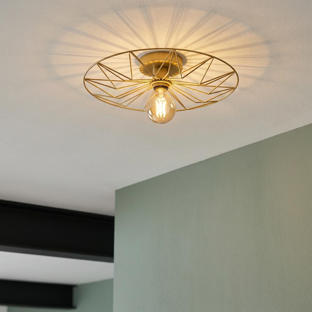 Gold retro flush ceiling light with a geometric wire frame casting radial shadows on a white ceiling.
