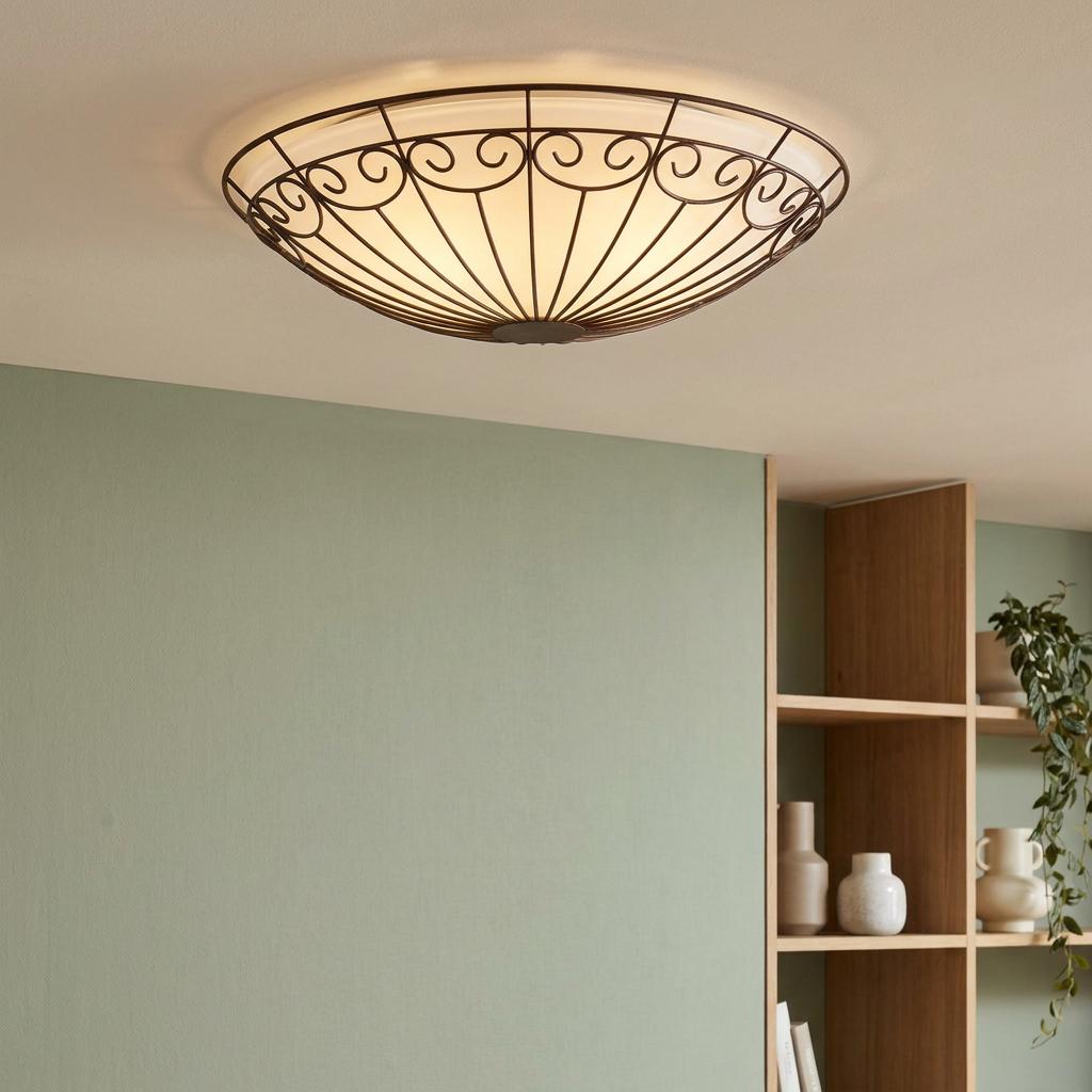 Eglo Colti flush ceiling light with brown wire scrollwork shade and white glass inner, mounted against a green wall.
