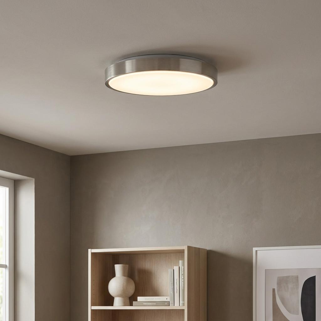 Modern nickel round LED flush ceiling light with a warm glow, mounted in a minimalist living room setting.