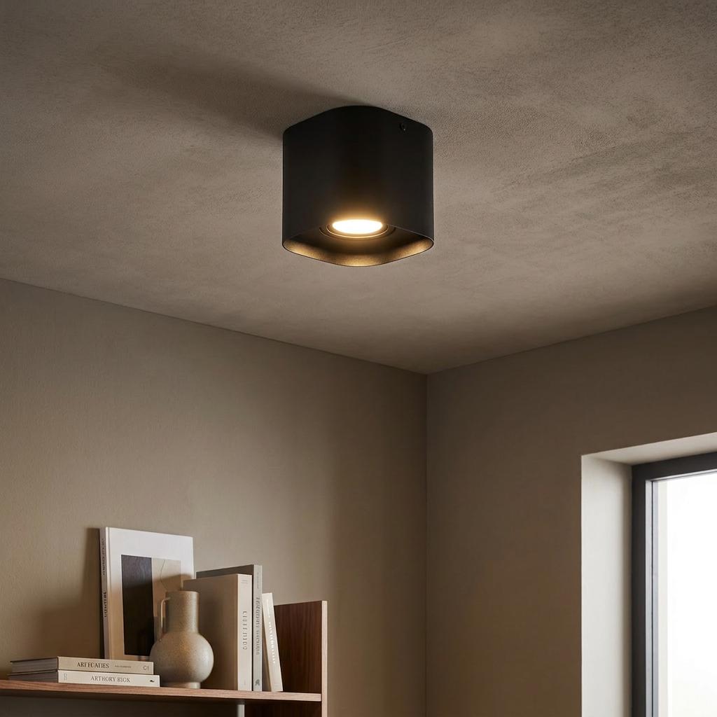 Modern square black flush ceiling light emitting a warm glow in a minimalist room.