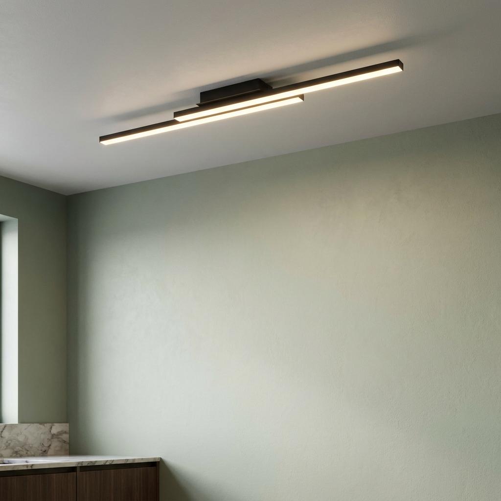 Modern black linear flush ceiling light with warm glowing bars mounted in a room with sage green walls.