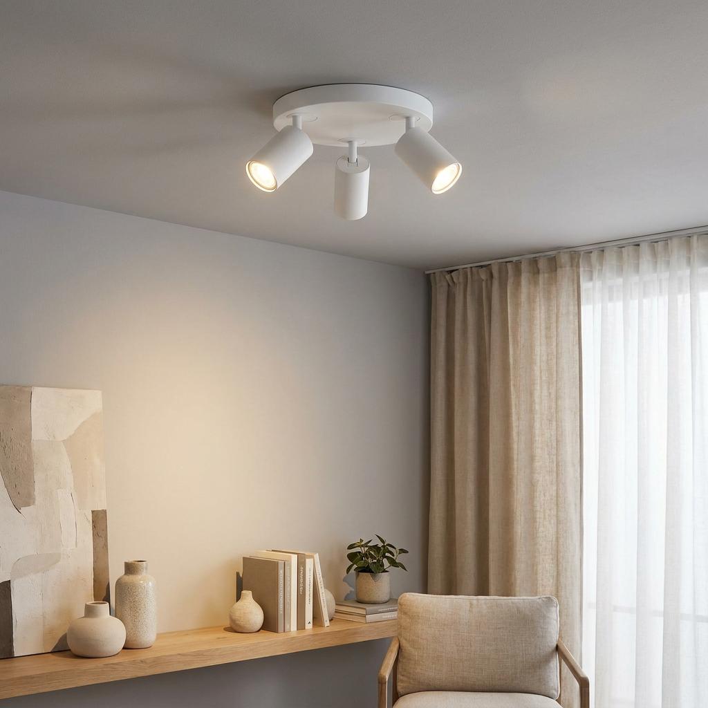Three-light white plate spotlight mounted on a ceiling, illuminating a neutral living space with warm light.
