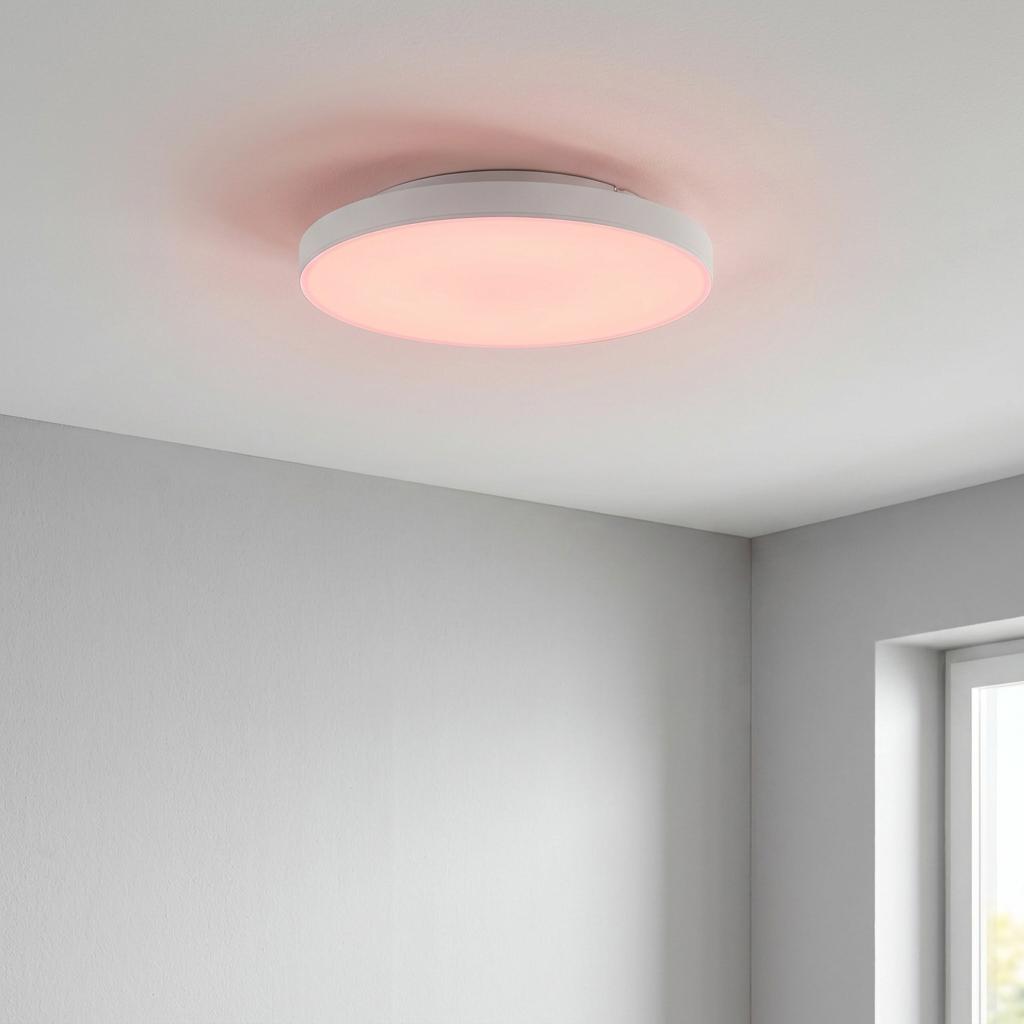 Round white LED flush ceiling light emitting a soft pink glow in a minimalist room.