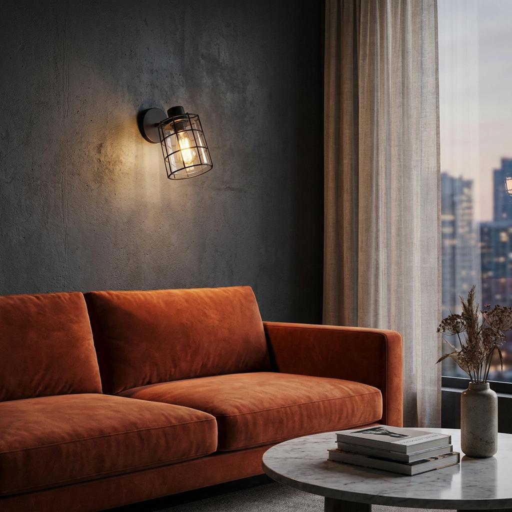 Industrial black wire wall light with smoked glass shade glowing above a burnt orange sofa on a dark textured wall.