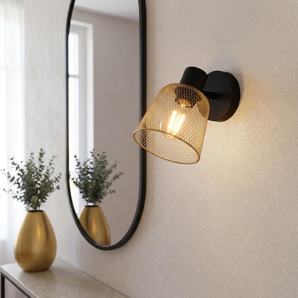 Eglo Coslada brass mesh wall light with a black base, shining on a wall beside an oval mirror.