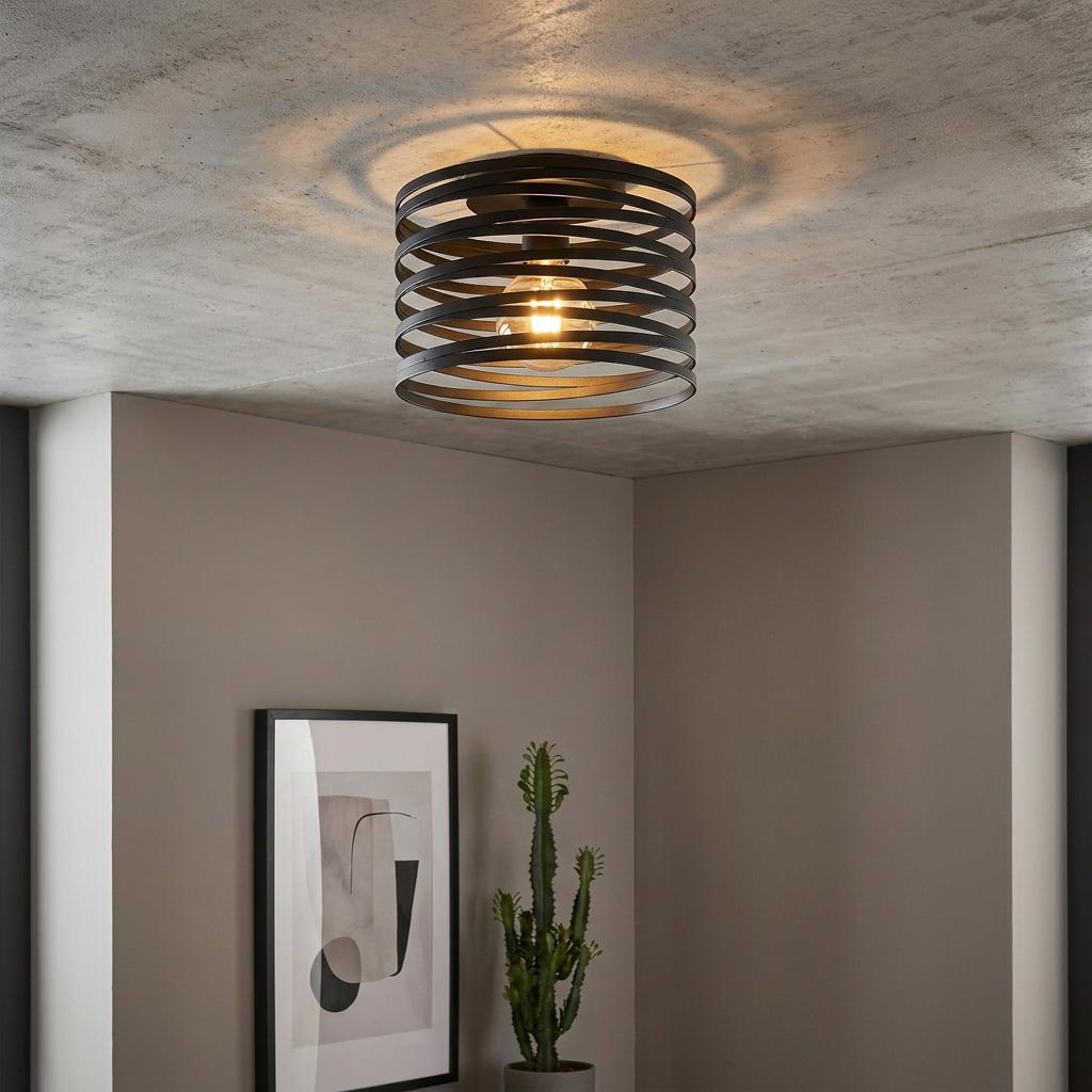 Black spiral metal flush ceiling light illuminating a modern room with a concrete-effect ceiling.