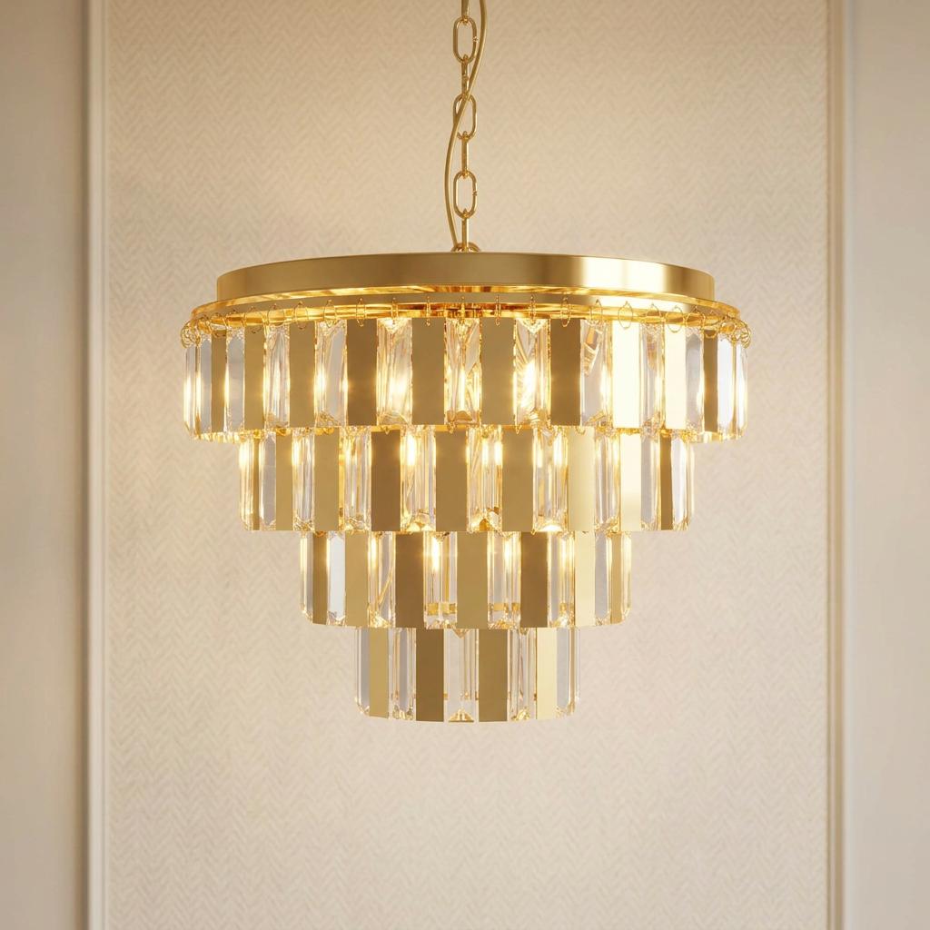A lit four-tiered chandelier with alternating brass plates and clear glass crystals hanging against a textured wall.