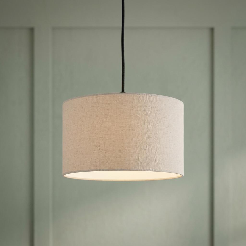 Eglo Feniglia round linen lampshade pendant light hanging in front of a green paneled wall, glowing warmly.