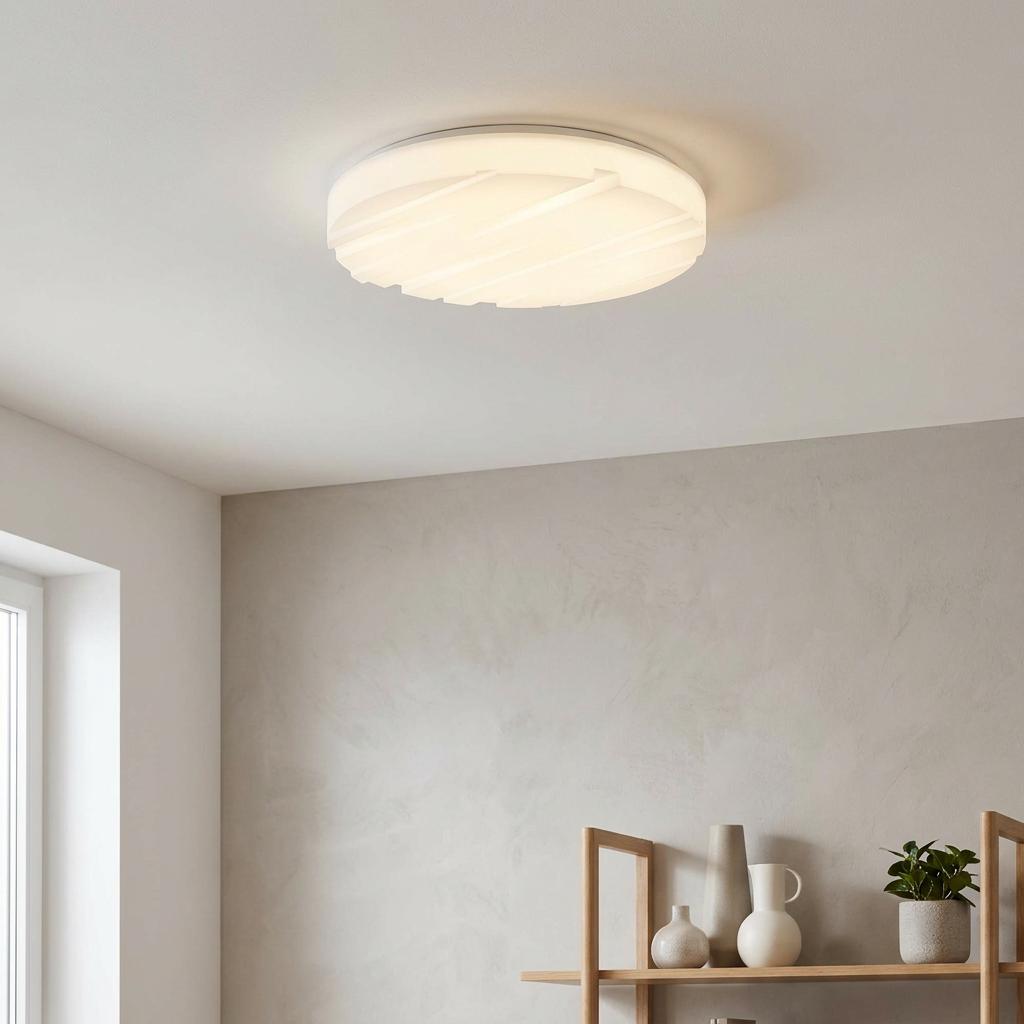 Round white LED flush ceiling light with a textured line pattern, glowing in a modern room.