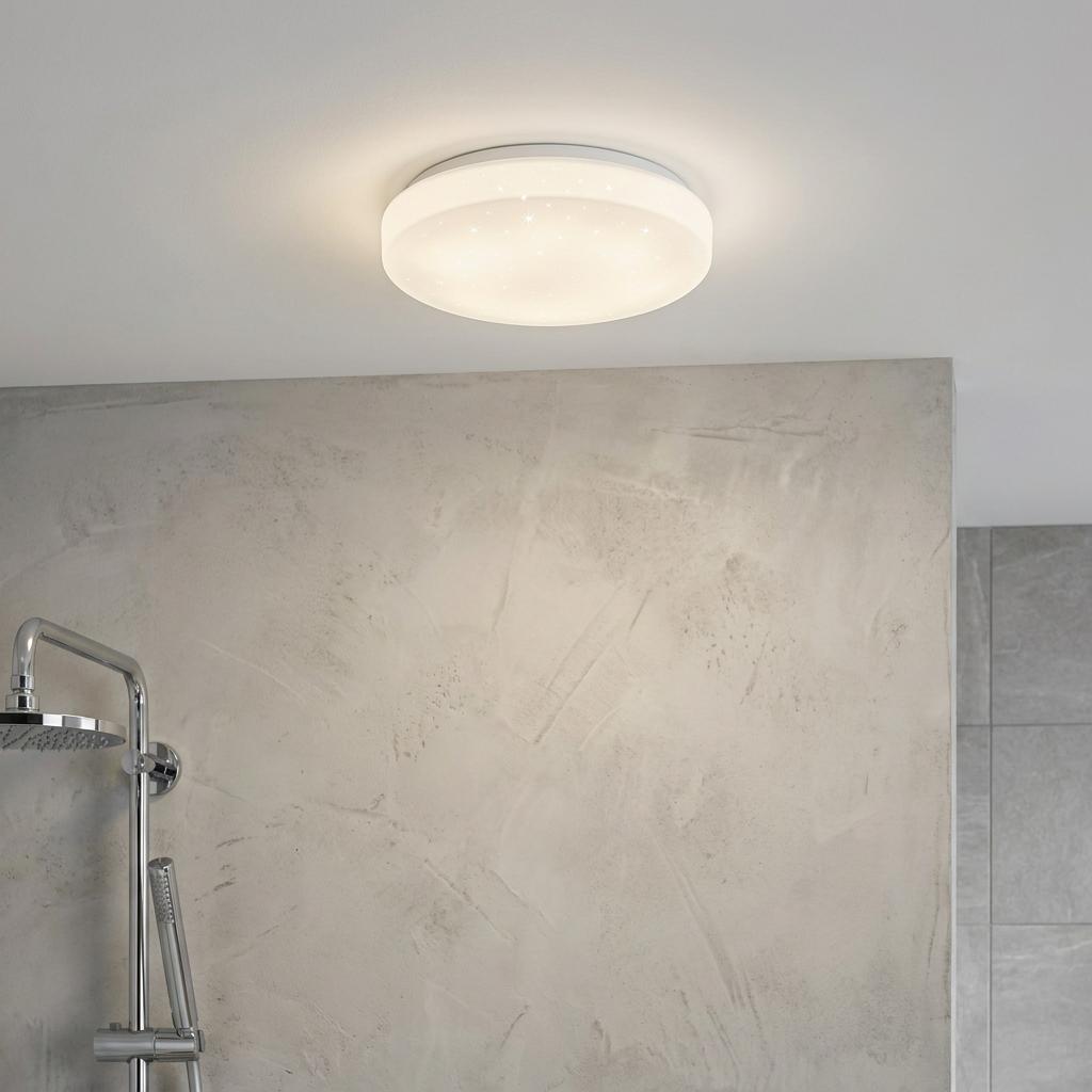 Illuminated round white flush ceiling light with a crystal effect in a modern bathroom above a shower.