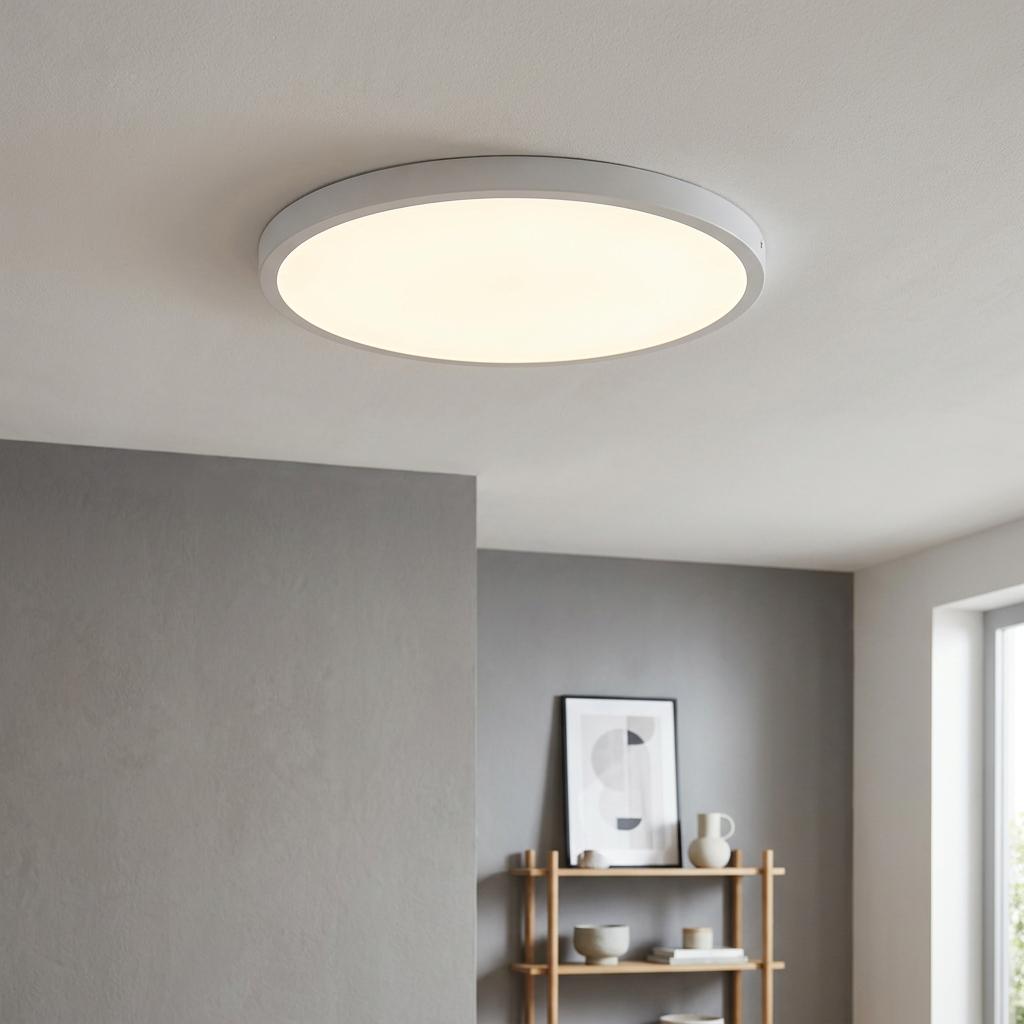 Large round white flush ceiling light glowing in a minimalist modern interior with grey walls.