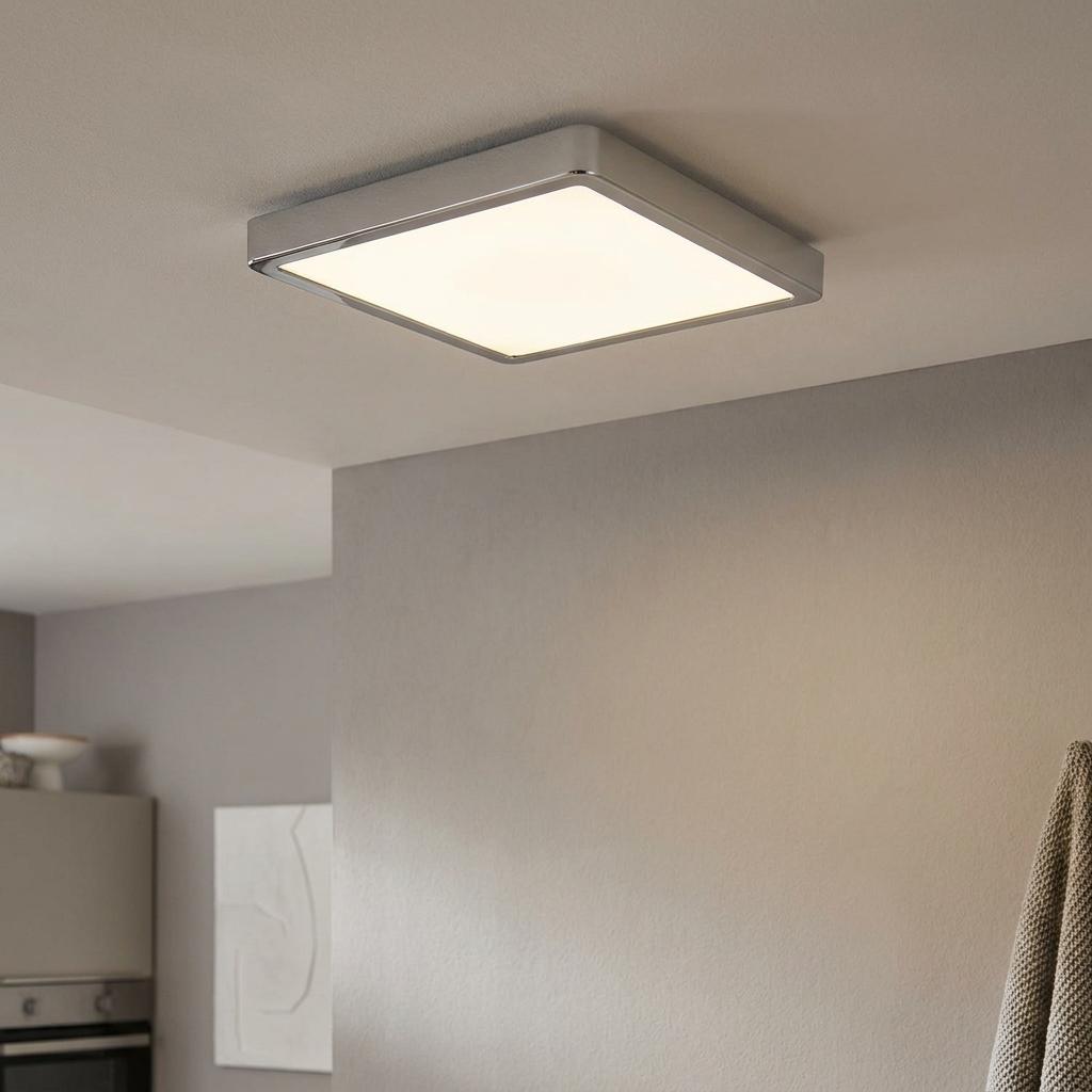 Square chrome LED ceiling light with a white diffuser, mounted in a modern grey interior.