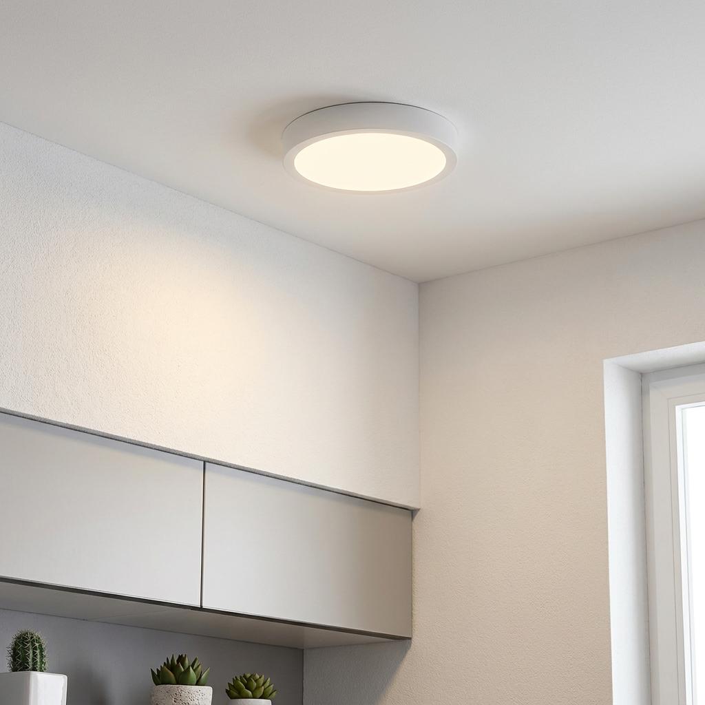 Eglo Fueva 5 round white LED flush ceiling light illuminating a white minimalist room above kitchen cabinets.