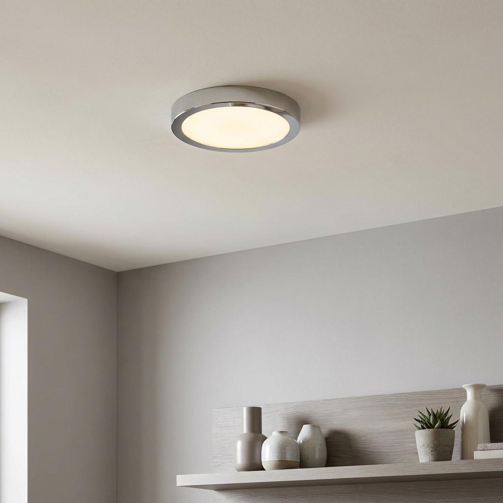 Round chrome LED flush ceiling light illuminates a modern interior with decorative vases on a shelf below.