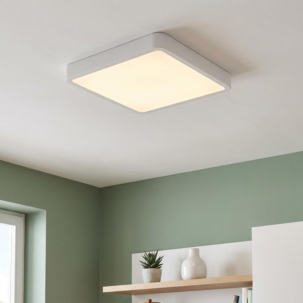 Square white LED flush ceiling light illuminating a room with soft green walls and a decorative shelf.