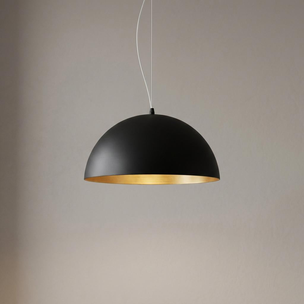 Matte black dome pendant light featuring a warm gold interior, hanging against a neutral background.