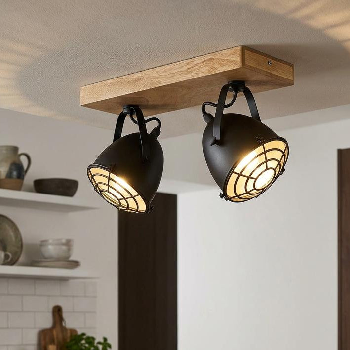 Industrial-style black twin spotlights with wire cages on a wooden bar, mounted on a kitchen ceiling.
