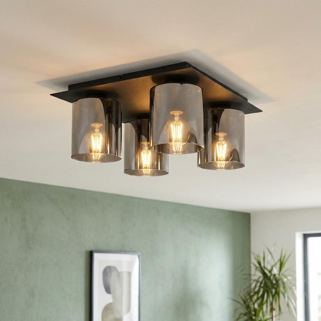Modern four-light flush ceiling fixture with smoked glass shades and a black base, illuminated in a light green room.