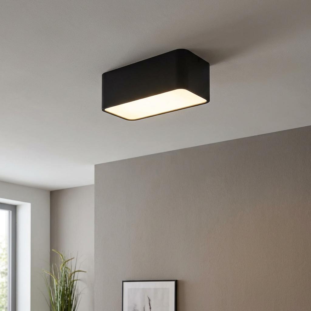 Rectangular black flush-mount ceiling light with a warm glow installed in a minimalist interior.