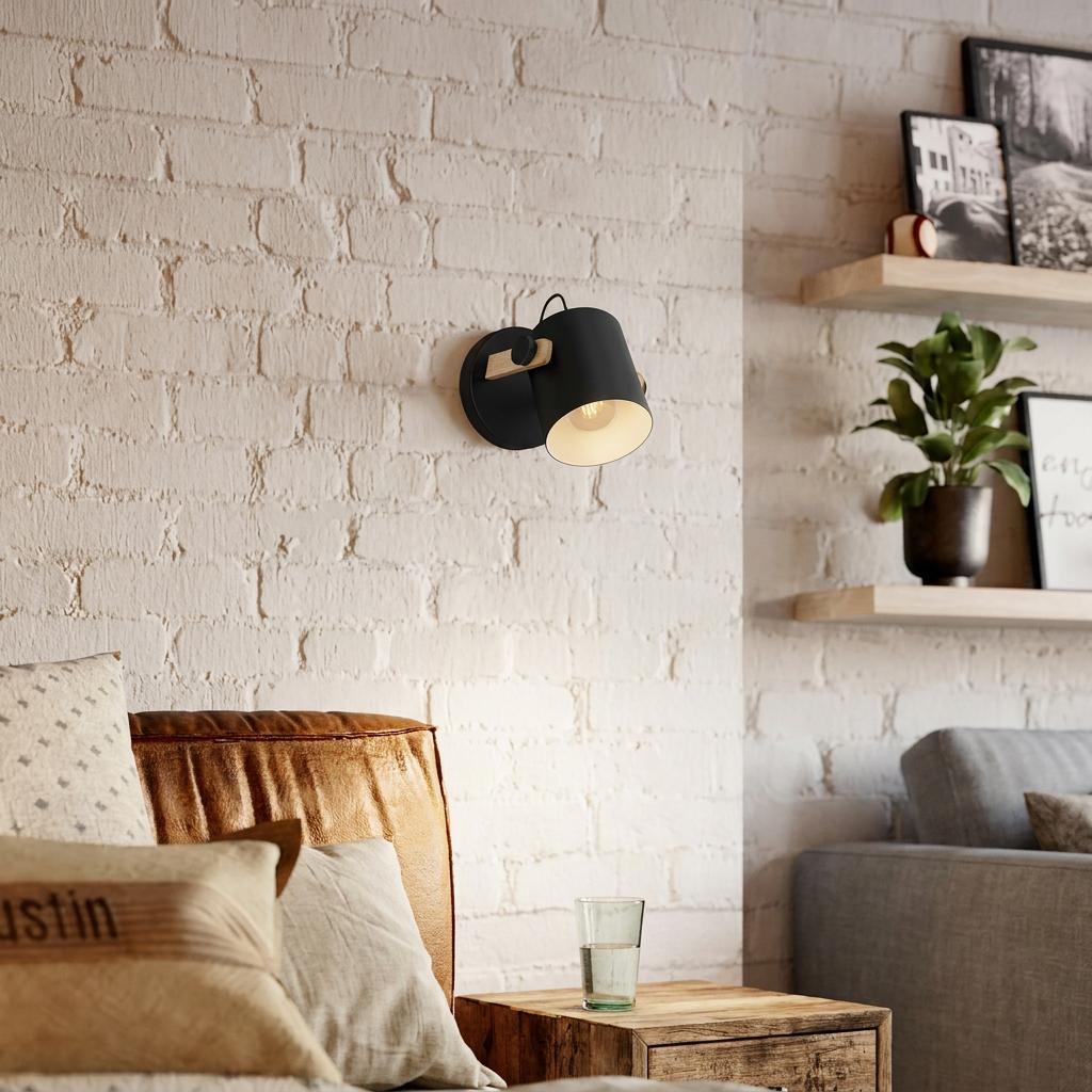 Black and wood pivoting wall light mounted on a white brick wall above a cozy seating area with leather sofa.