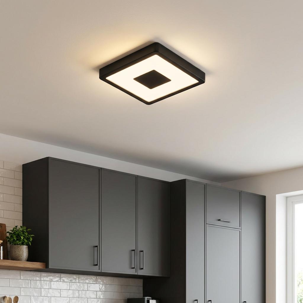 Square black LED flush ceiling light illuminating a modern kitchen with dark grey cabinets.