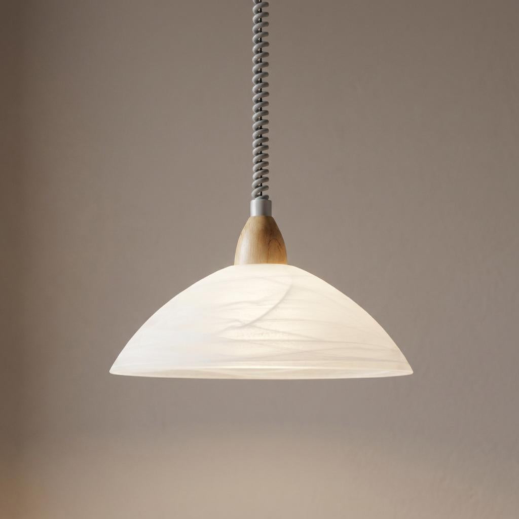 White alabaster glass pendant light with beech wood accents and a coiled cable hanging against a neutral wall.