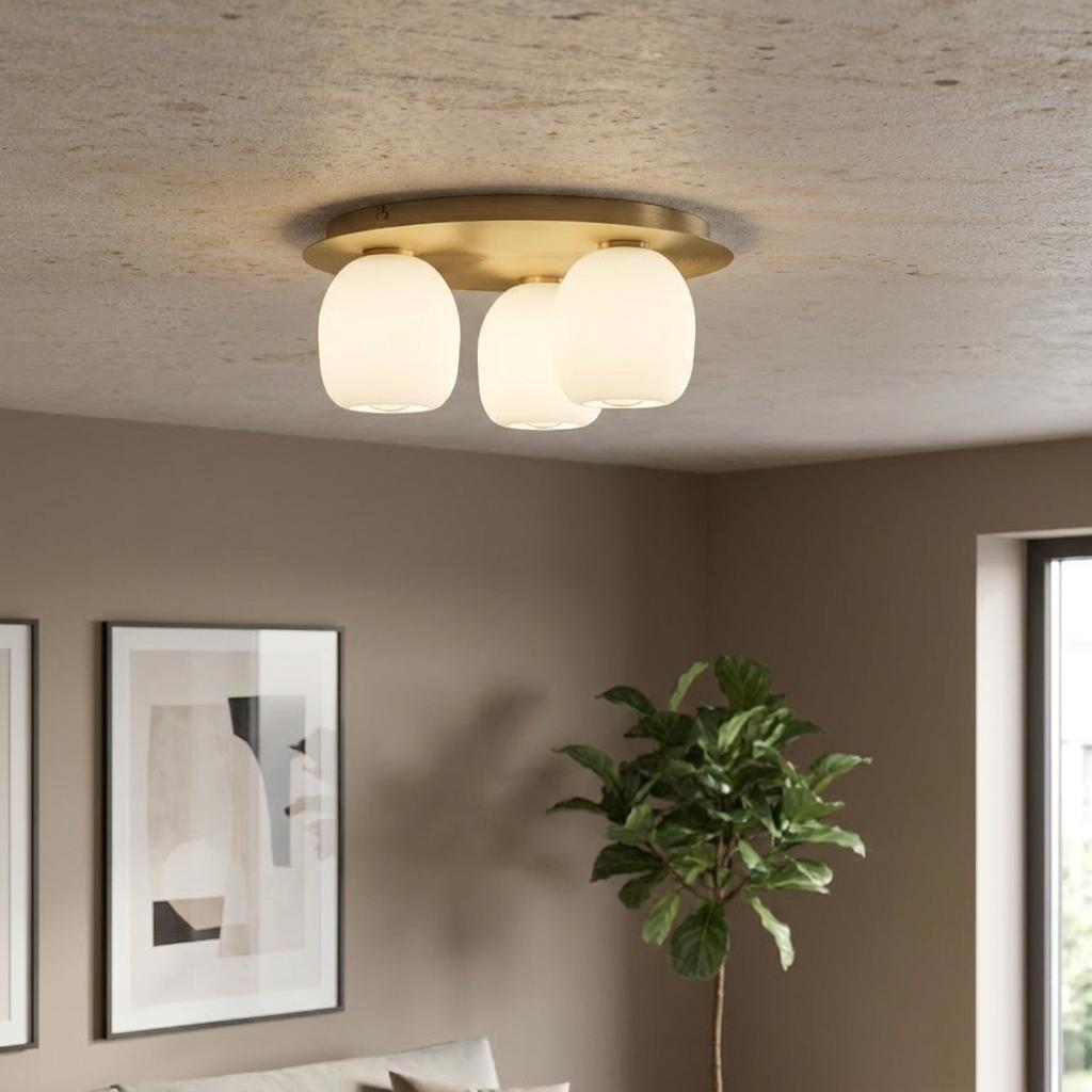 Modern three-light brass flush mount with glowing opal glass shades in a contemporary living space.