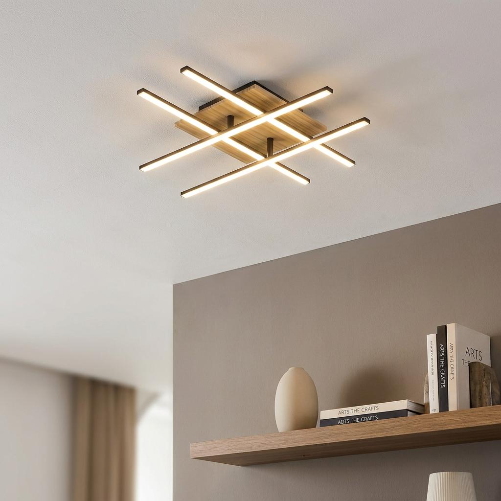 Modern criss-cross LED ceiling flush light with black accents and a wooden base in a contemporary room.
