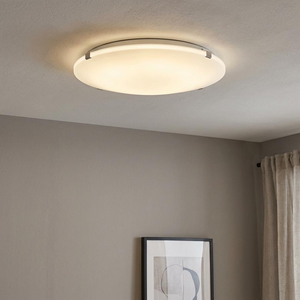 A round Eglo Mars white satin glass flush ceiling light illuminating a minimalist room.