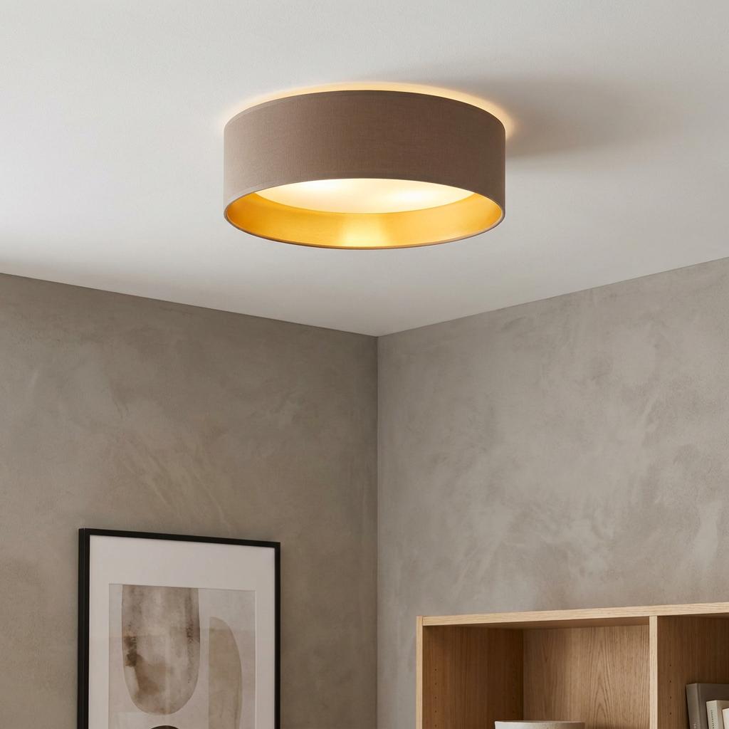 Round flush ceiling light with a cappuccino fabric shade and warm gold interior glowing on a white ceiling.